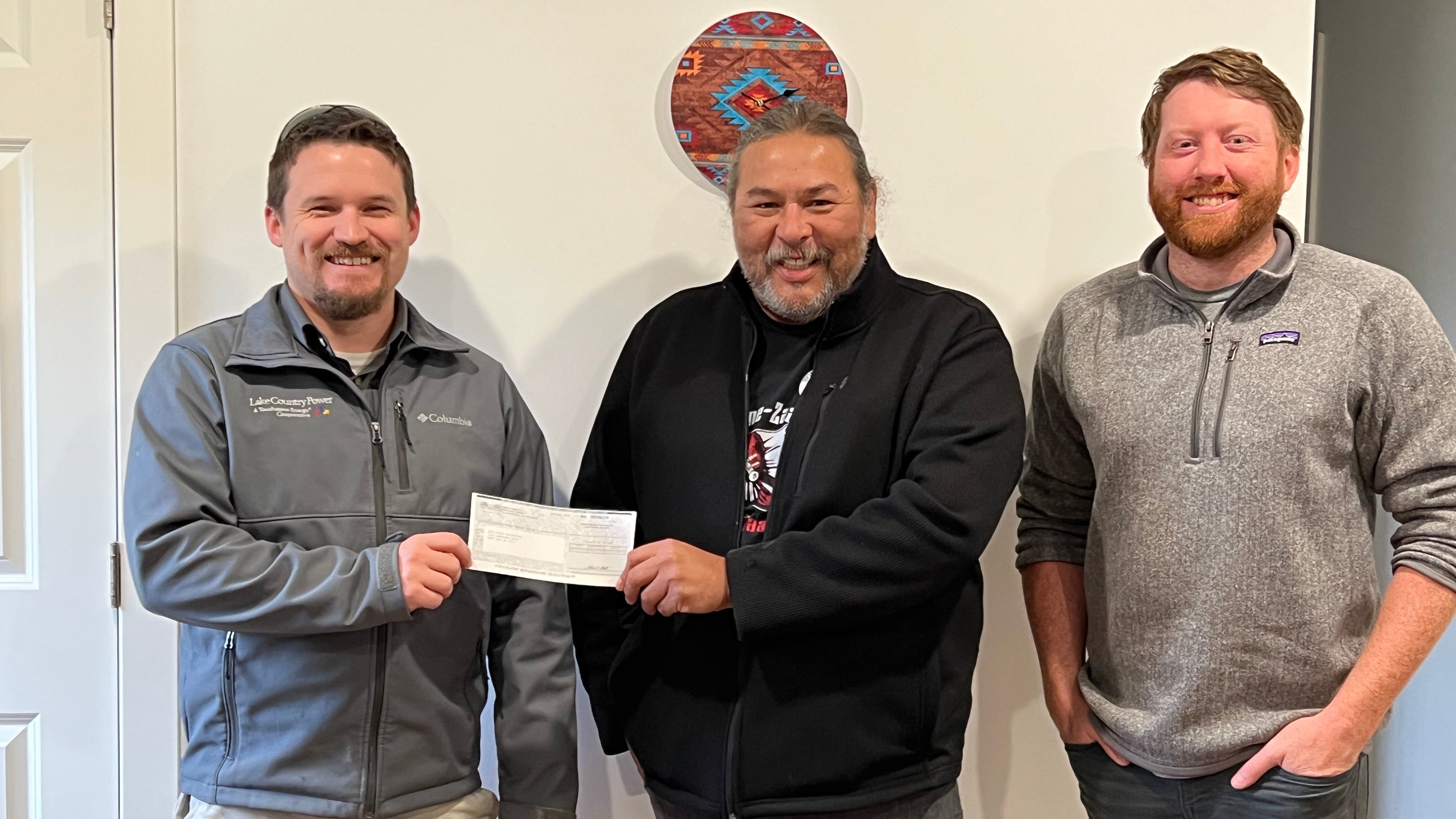 Three people posing with a check