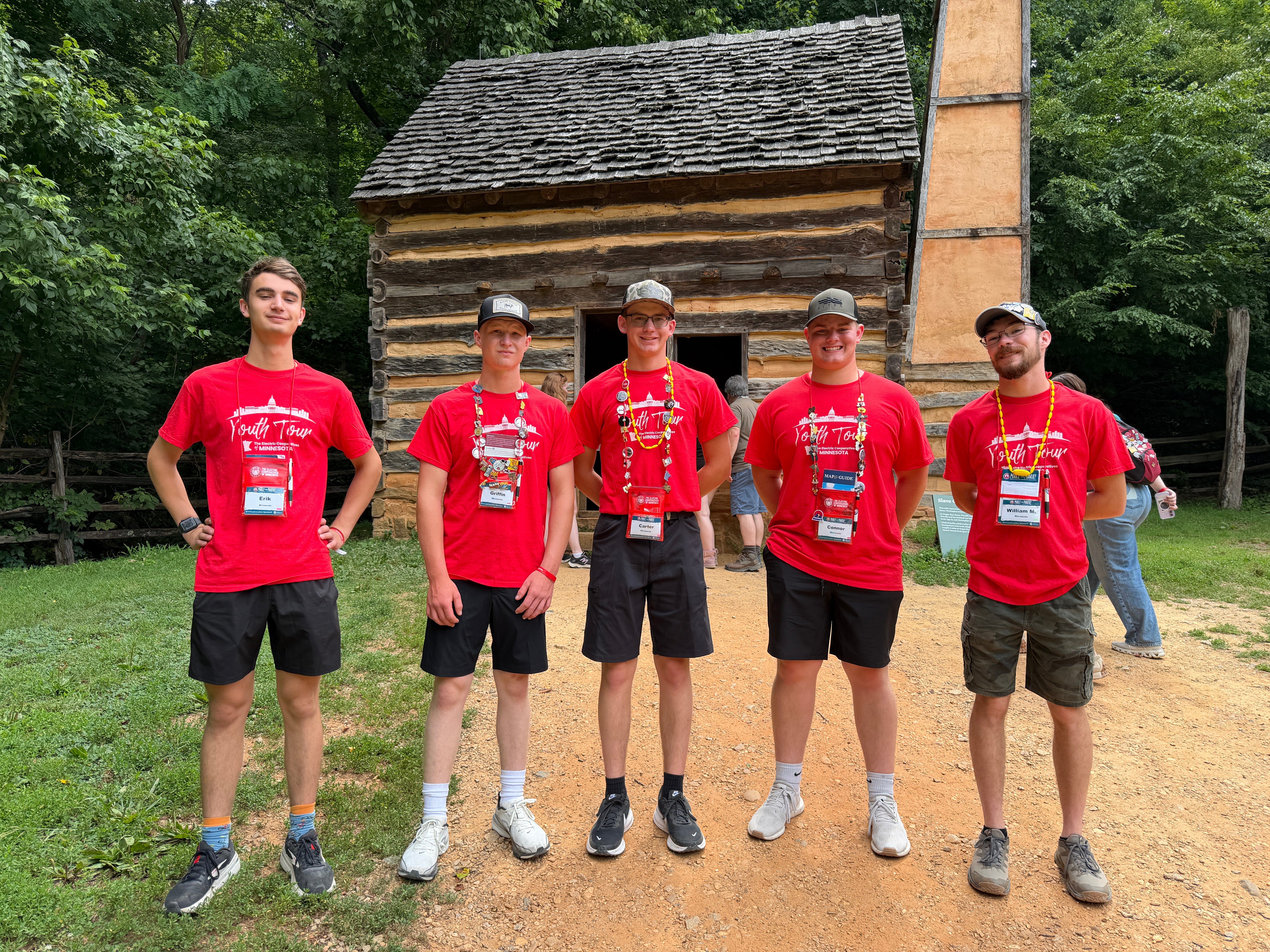 Five students in red shirts outside a camp