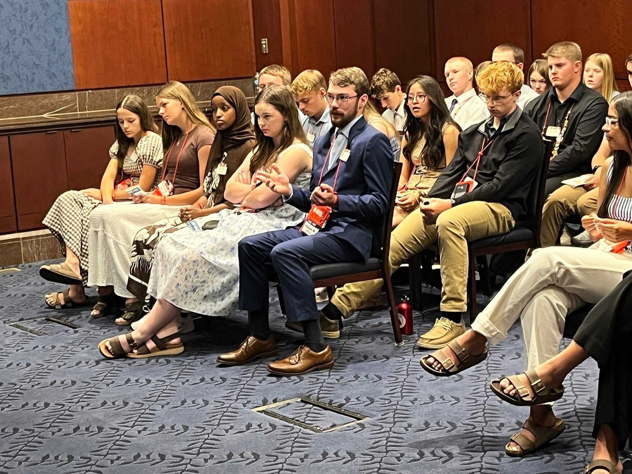 Students in a conference room and one speaking