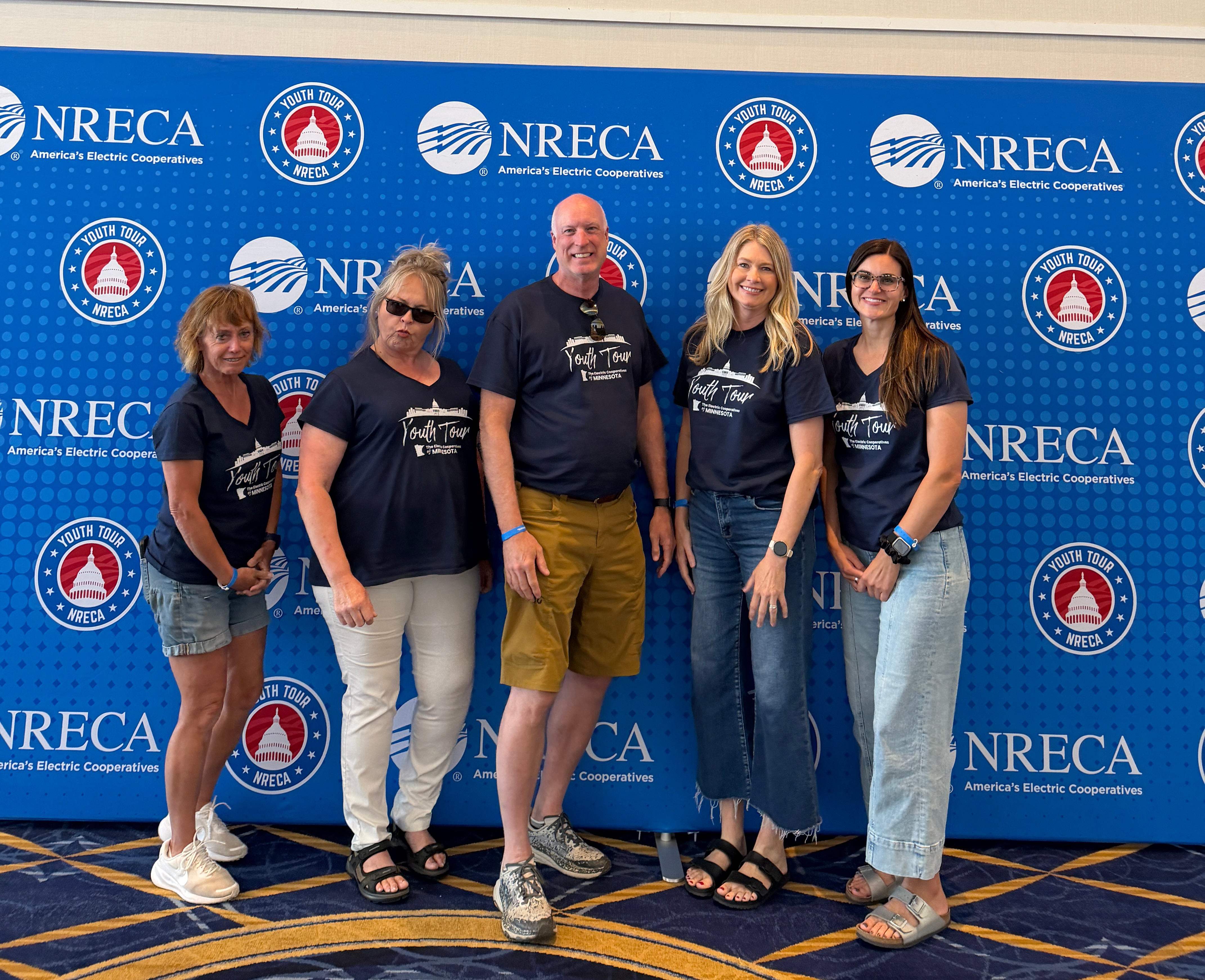 Volunteers in blue shirts with an NRECA Youth Tour banner behidn them