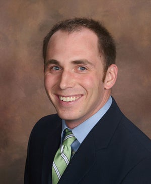 Jake Chrzanowski in a black suit, blue shirt and green tie
