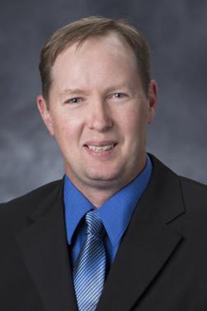Jason Long in black jacket and blue shirt/tie