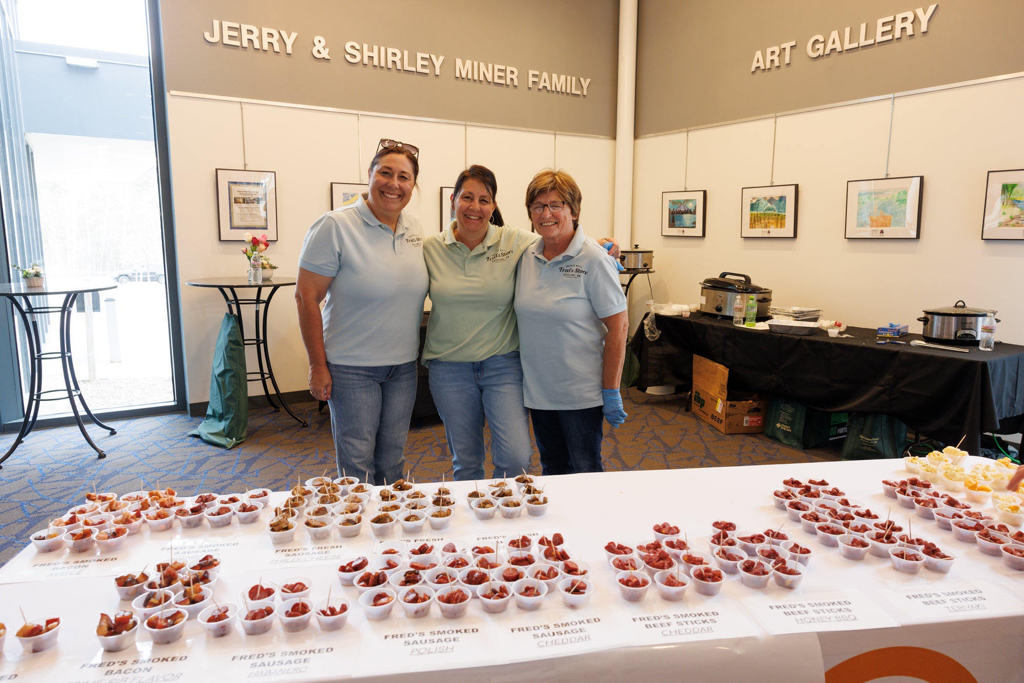 THree people standing at a table with sausage