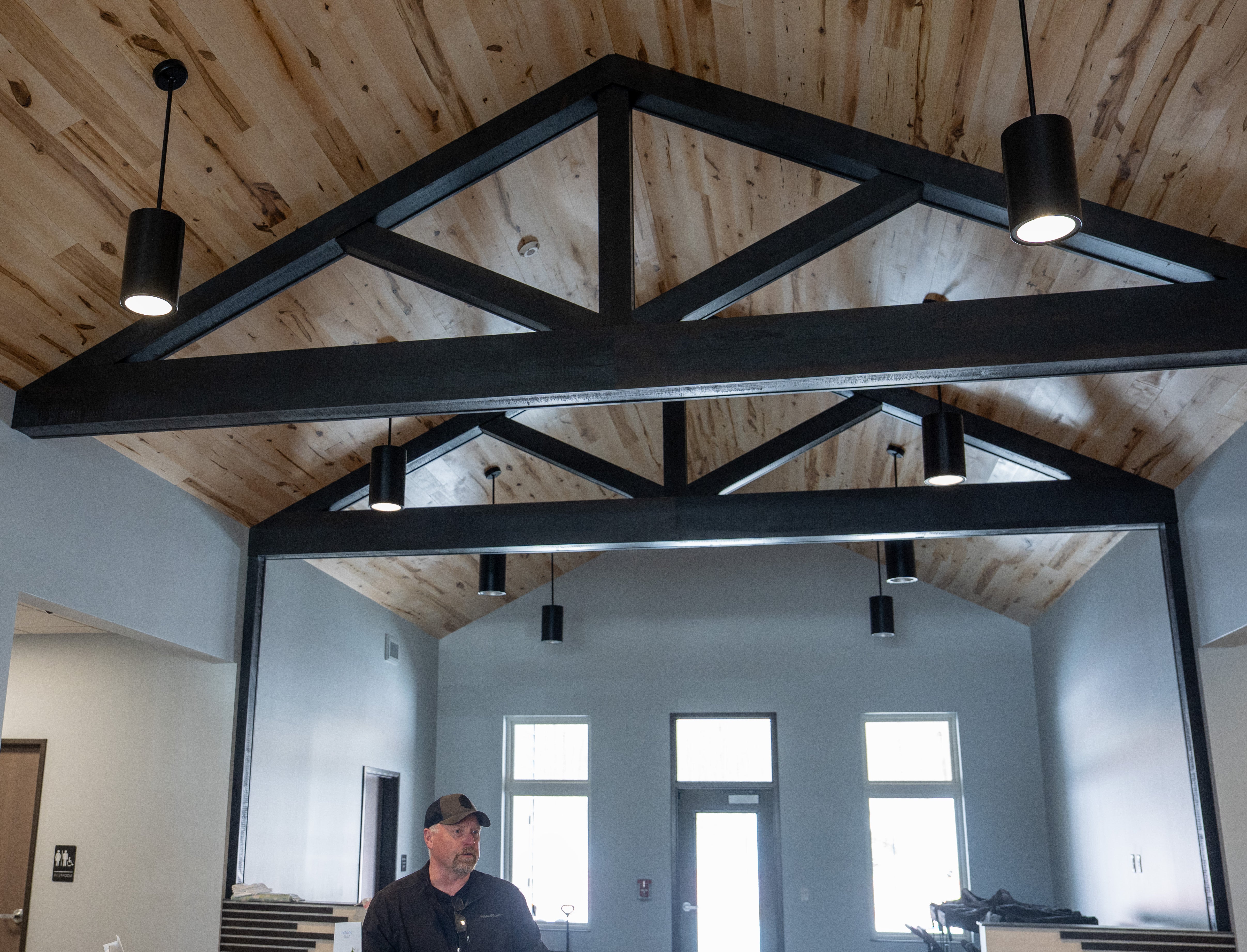 man at the counter of the entrance to a daycare, with wood ceiling beams shown