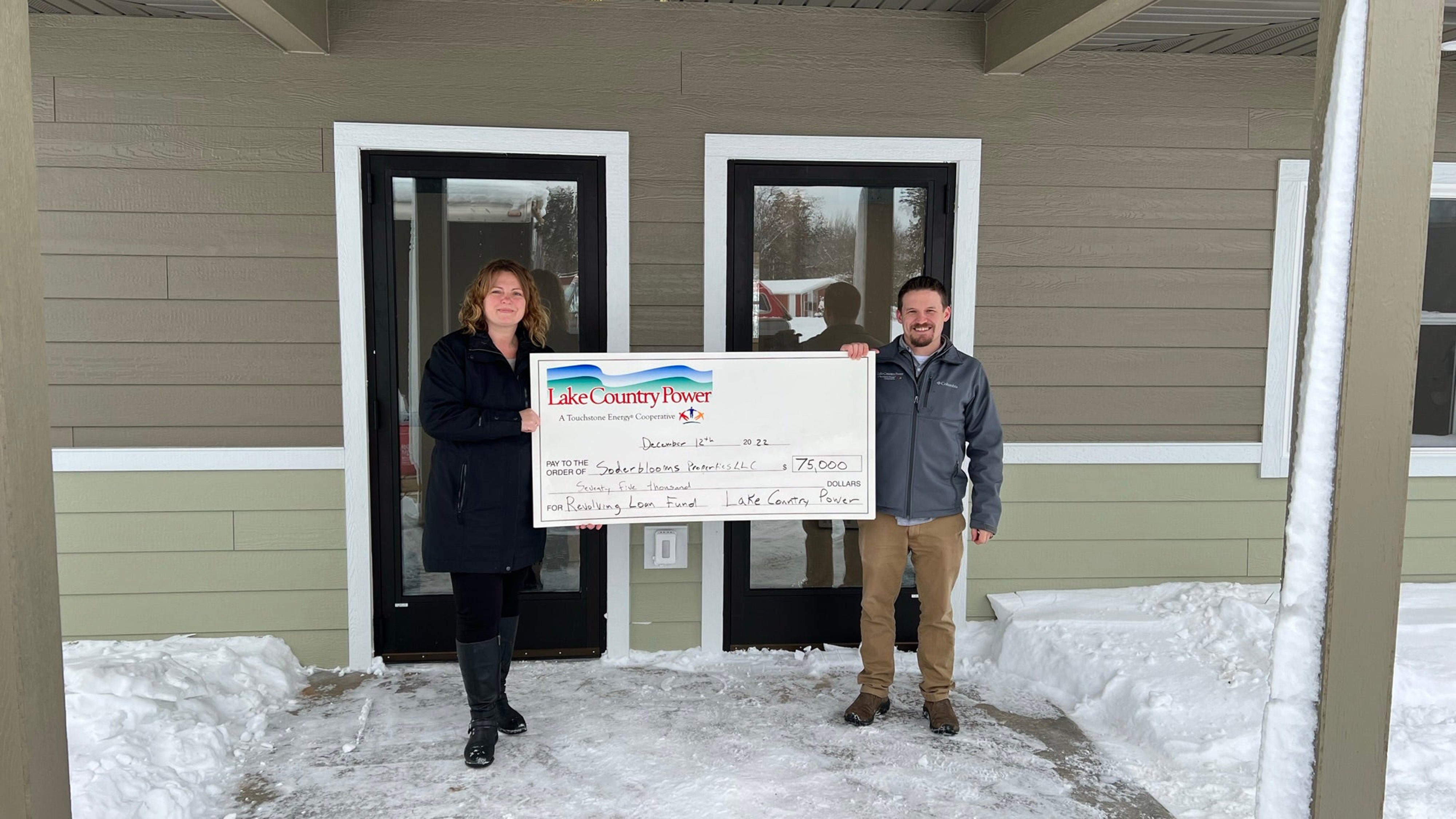 Two people standing with large check