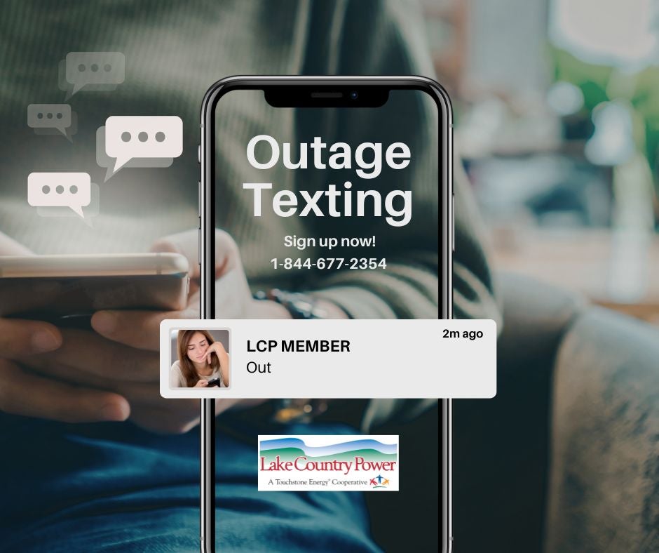A promotional graphic encourages Lake Country Power members to sign up for outage text alerts. A smartphone centered on the image displays the words "Outage Texting" with the message "Sign up now! 1-844-677-2354." A sample text notification reading "LCP MEMBER – Out" appears across the lower portion of the phone. The background shows a person holding a smartphone with faint chat bubble icons, and the Lake Country Power logo is displayed at the bottom.